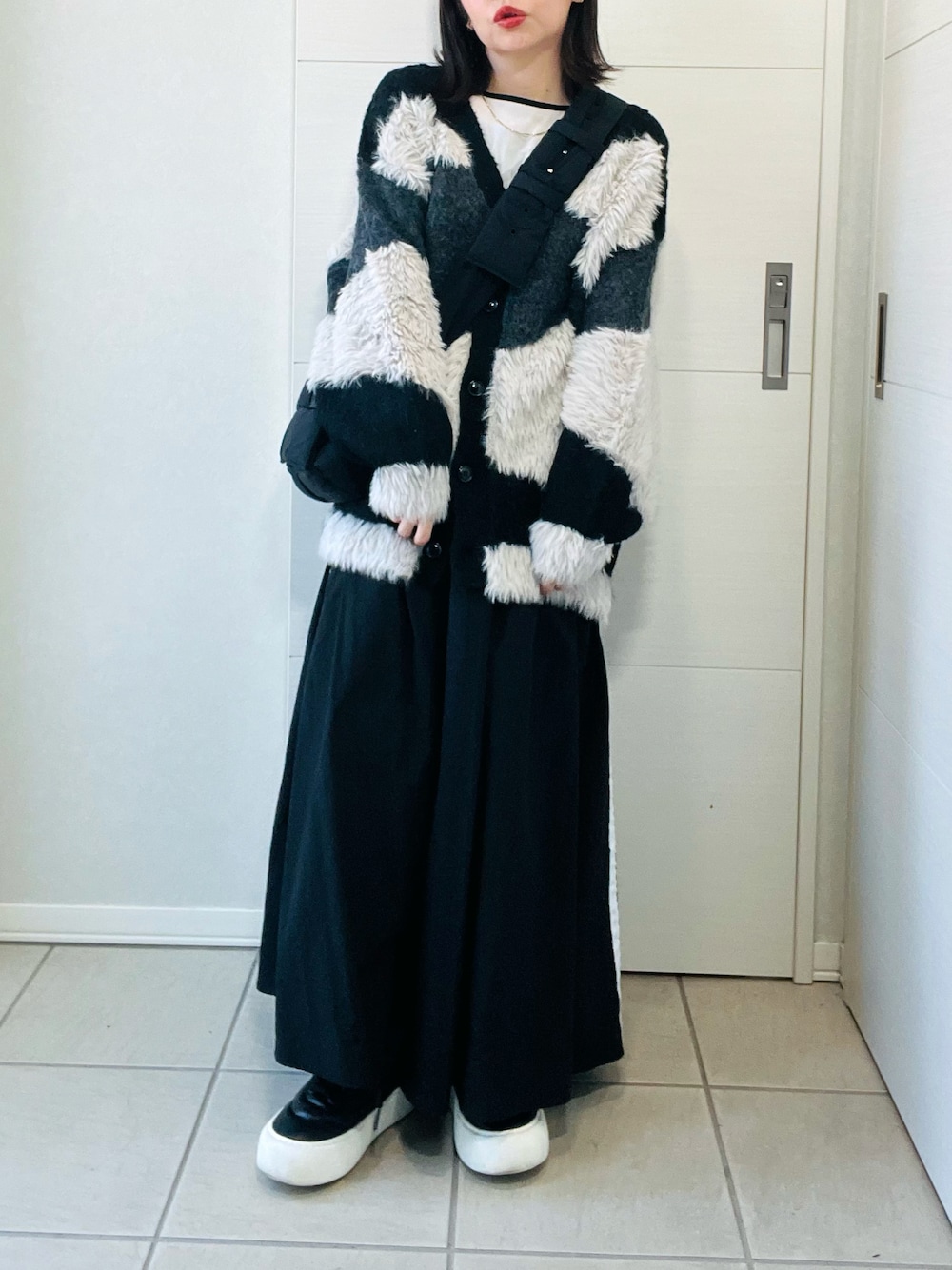 ブラック系のカーディガン/ボレロ、ブラック系のスニーカー、ブラック系のスカートを着用したレディースの秋コーディネートの1枚目の写真