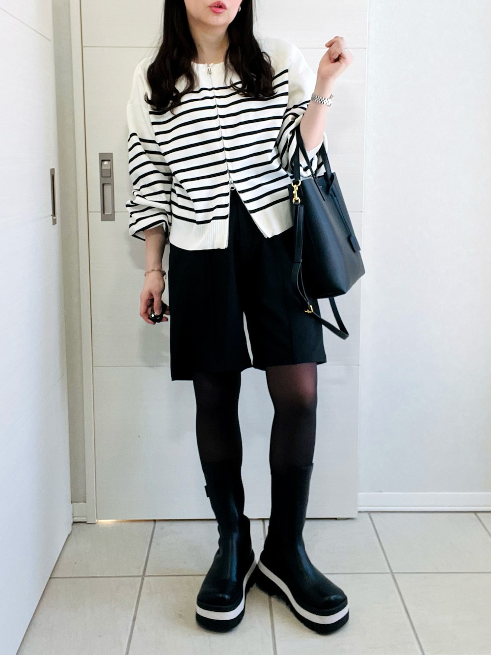 ホワイト系のカーディガン/ボレロ、ブラック系のその他パンツ、ブラック系のブーツを着用したレディースの冬コーディネートの1枚目の写真