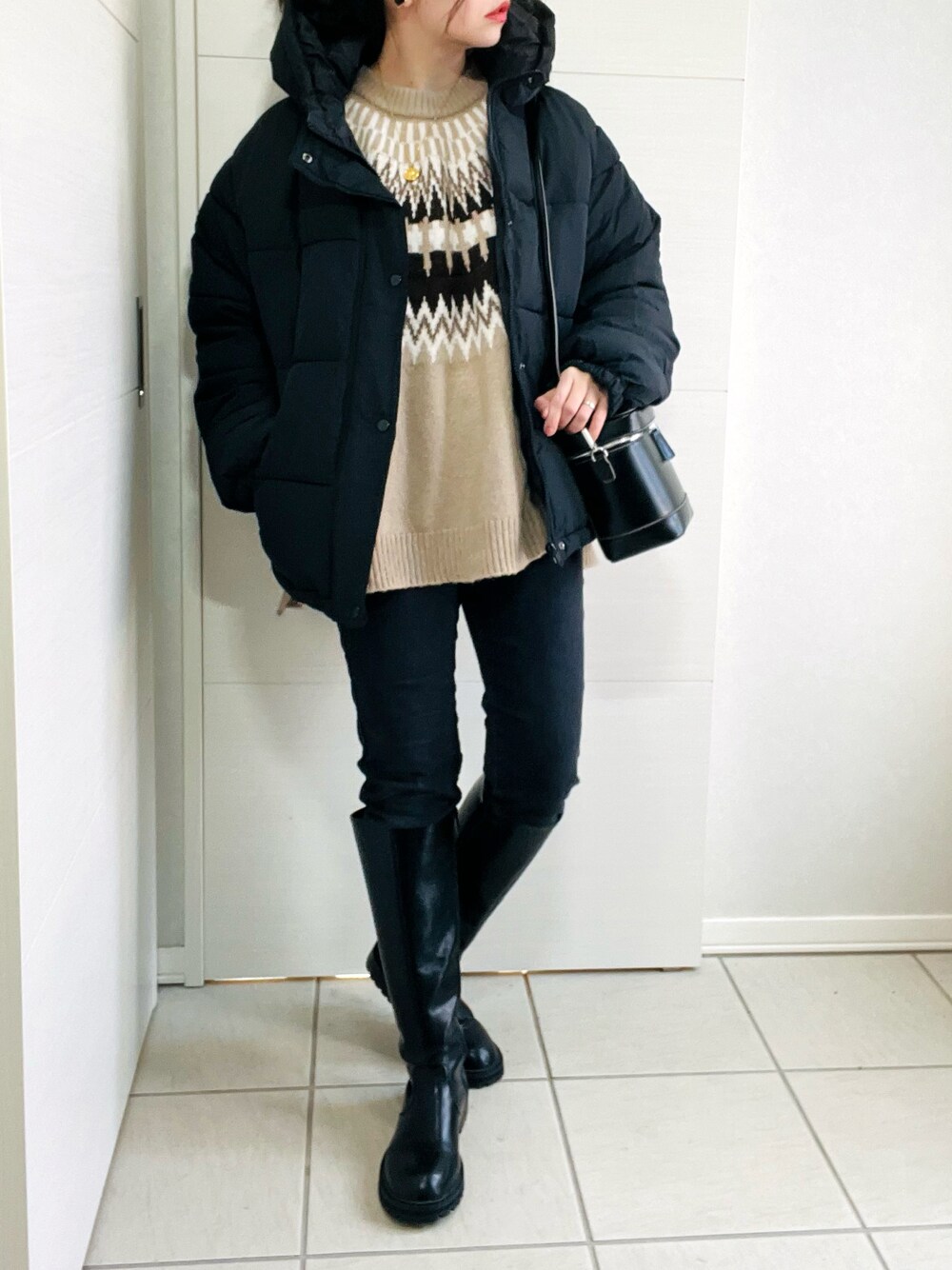 ブラック系のダウンジャケット/コート、ベージュ系のニット/セーター、ブラック系のデニムパンツを着用したレディースの冬コーディネートの1枚目の写真