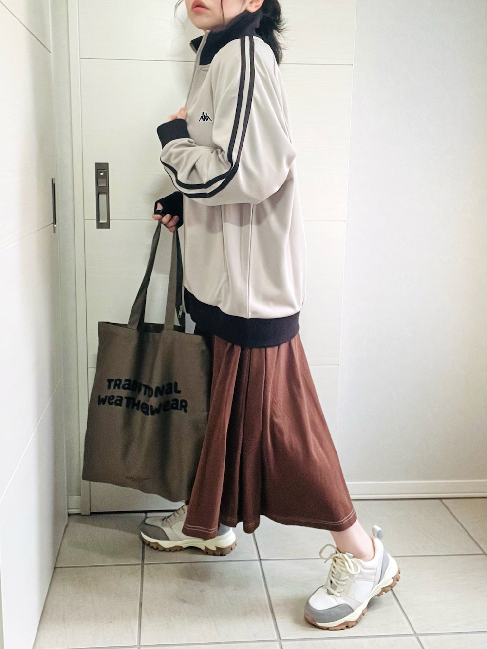 ベージュ系のジャージ、ブラウン系のワンピース、ベージュ系のスニーカーを着用したレディースの秋コーディネートの1枚目の写真
