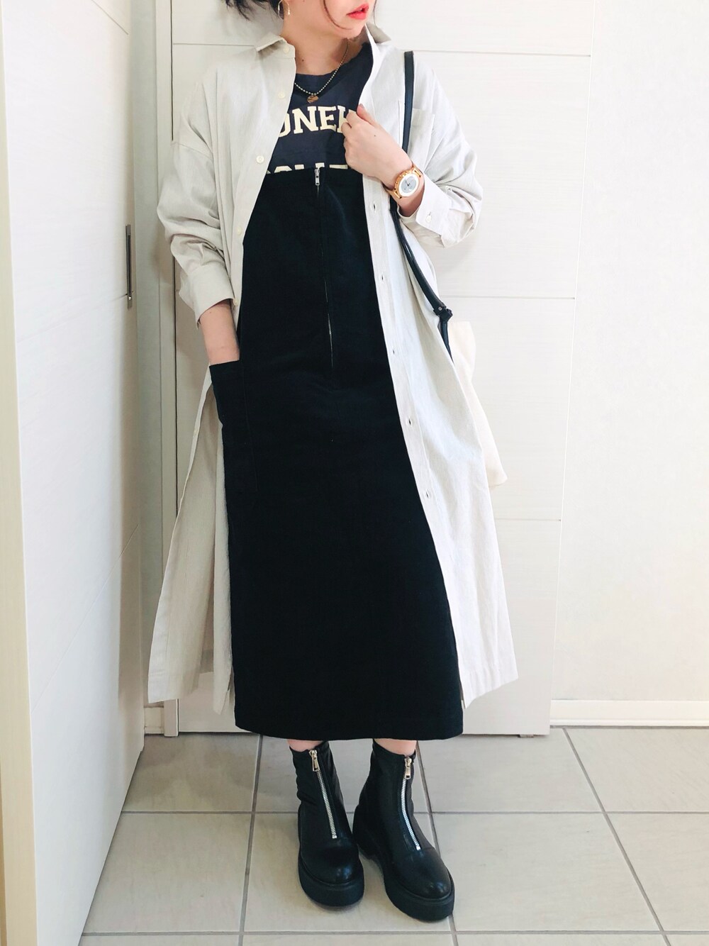 ベージュ系のワンピース、ブルー系のTシャツ/カットソー、ブラック系のジャンパースカートを着用したレディースの冬コーディネートの1枚目の写真