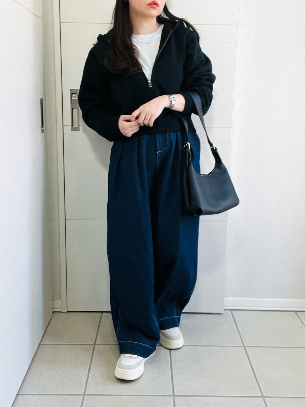 ブルー系のデニムパンツ、ホワイト系のスニーカー、ブラック系のショルダーバッグを着用したレディースの春コーディネートの1枚目の写真