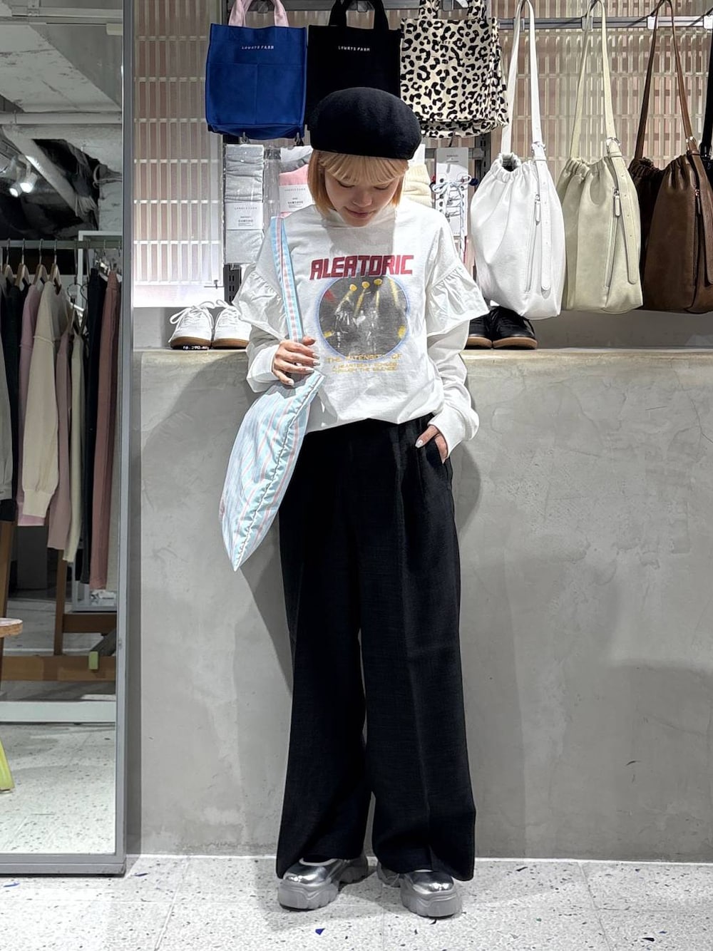 グレー系のスラックス、その他のトートバッグ、ホワイト系のTシャツ/カットソーを着用したレディースの春コーディネートの1枚目の写真