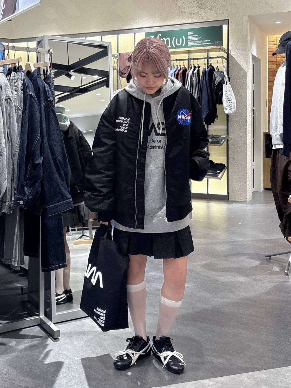 グレー系のスカート、グレー系のTシャツ/カットソー、ブラック系のブルゾンを着用したレディースの秋コーディネートの1枚目の写真