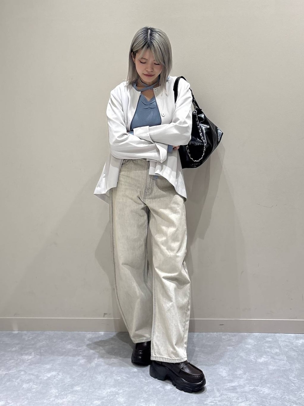 ベージュ系のデニムパンツ、ホワイト系のテーラードジャケット、ブラック系のショルダーバッグを着用したレディースの冬コーディネートの1枚目の写真