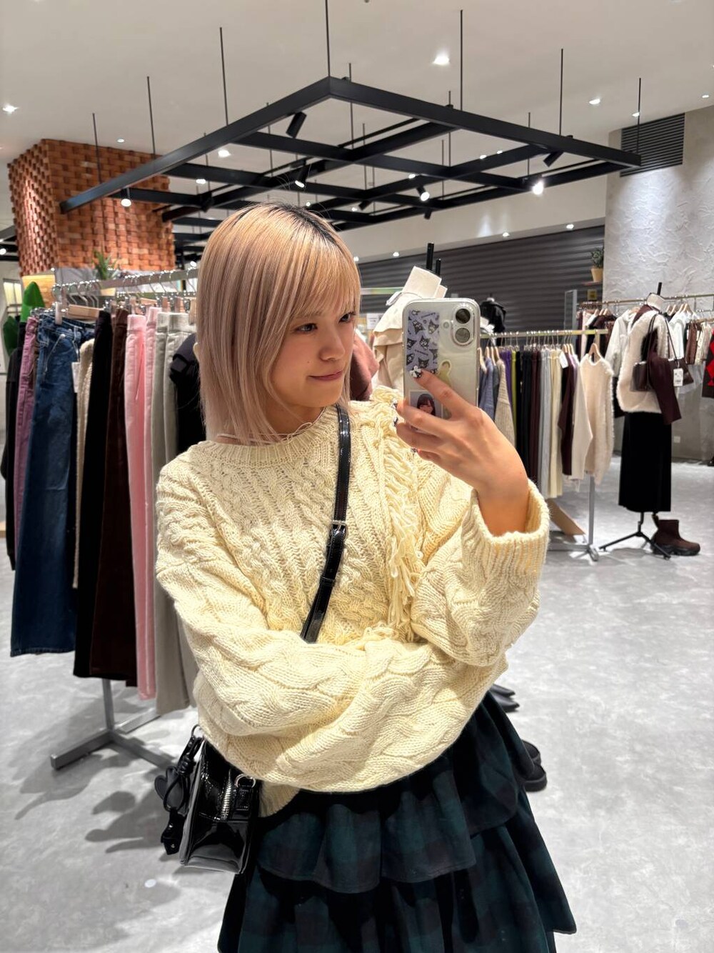 グリーン系のスカート、ホワイト系のポロシャツ、ブラック系のボストンバッグを着用したレディースの冬コーディネートの1枚目の写真