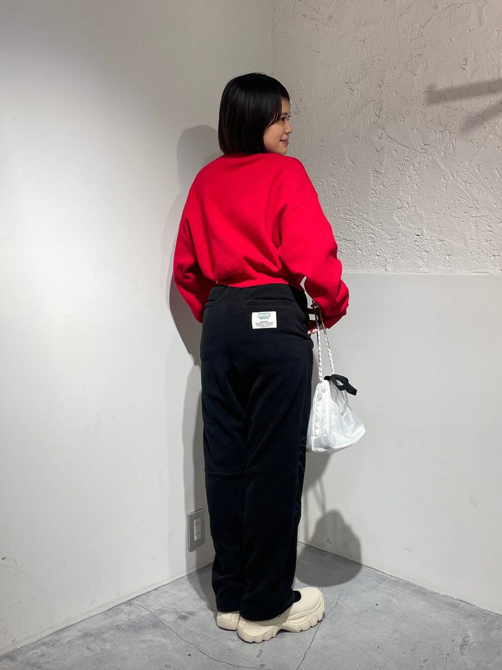 ブラック系のその他パンツ、ホワイト系のスニーカー、レッド系のニット/セーターを着用したレディースの秋コーディネートの1枚目の写真