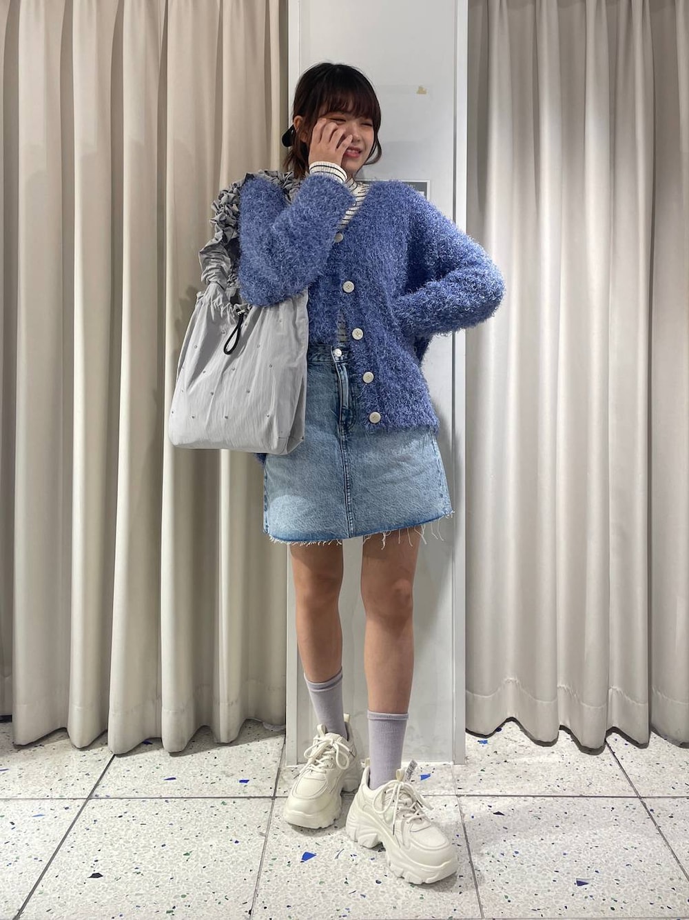 ホワイト系のカーディガン/ボレロ、グレー系のトートバッグ、ブルー系のスカートを着用したレディースの冬コーディネートの1枚目の写真