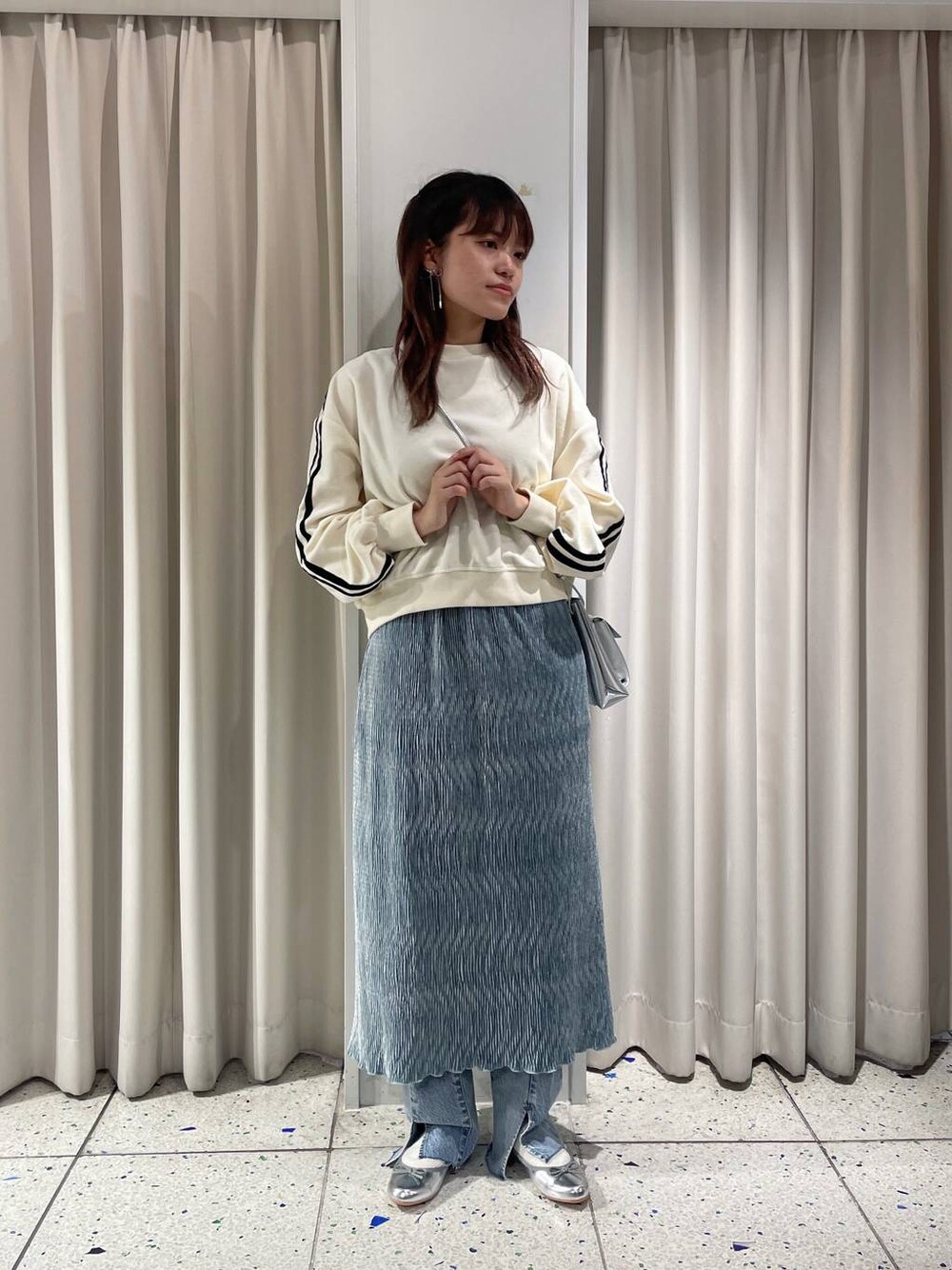 グレー系のバレエシューズ、ブルー系のデニムパンツ、ホワイト系のスウェットを着用したレディースの冬コーディネートの1枚目の写真