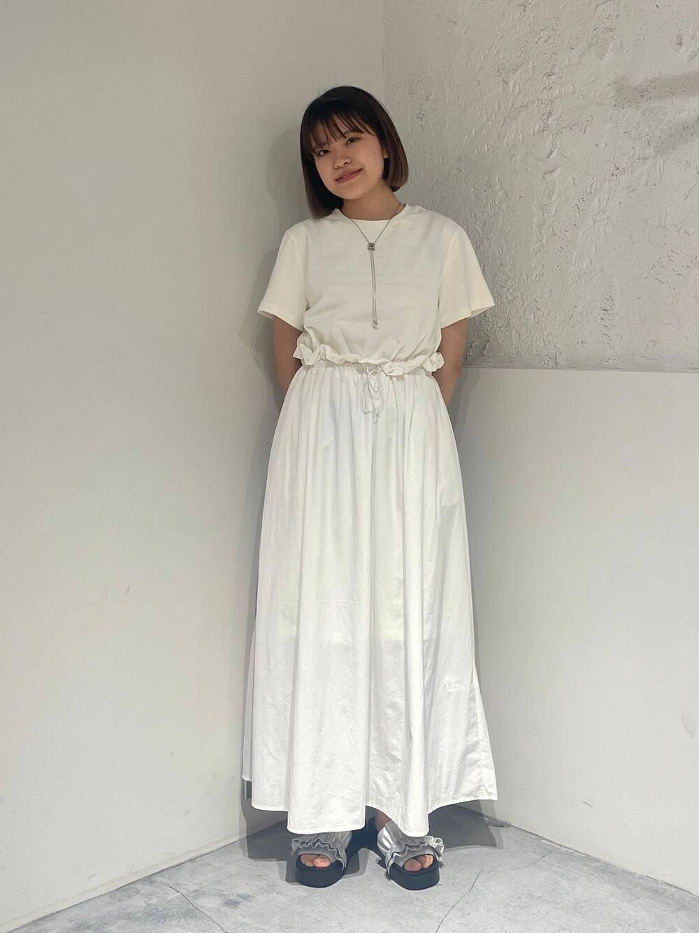 シルバー系のサンダル、ホワイト系のワンピース、シルバー系のネックレスを着用したレディースの春コーディネートの1枚目の写真