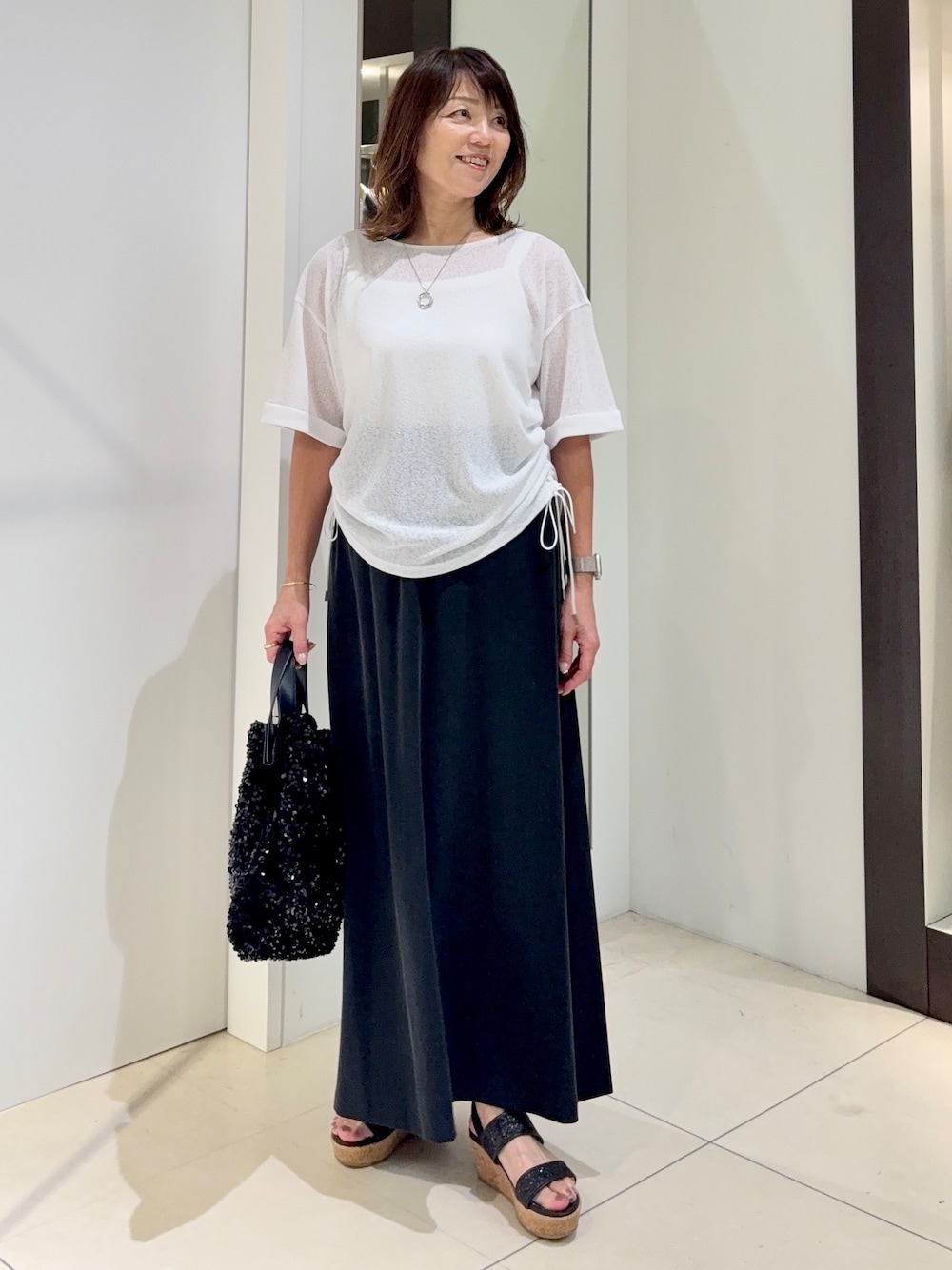 ホワイト系のTシャツ/カットソー、ブラック系のスカートを着用したレディースの夏コーディネートの1枚目の写真