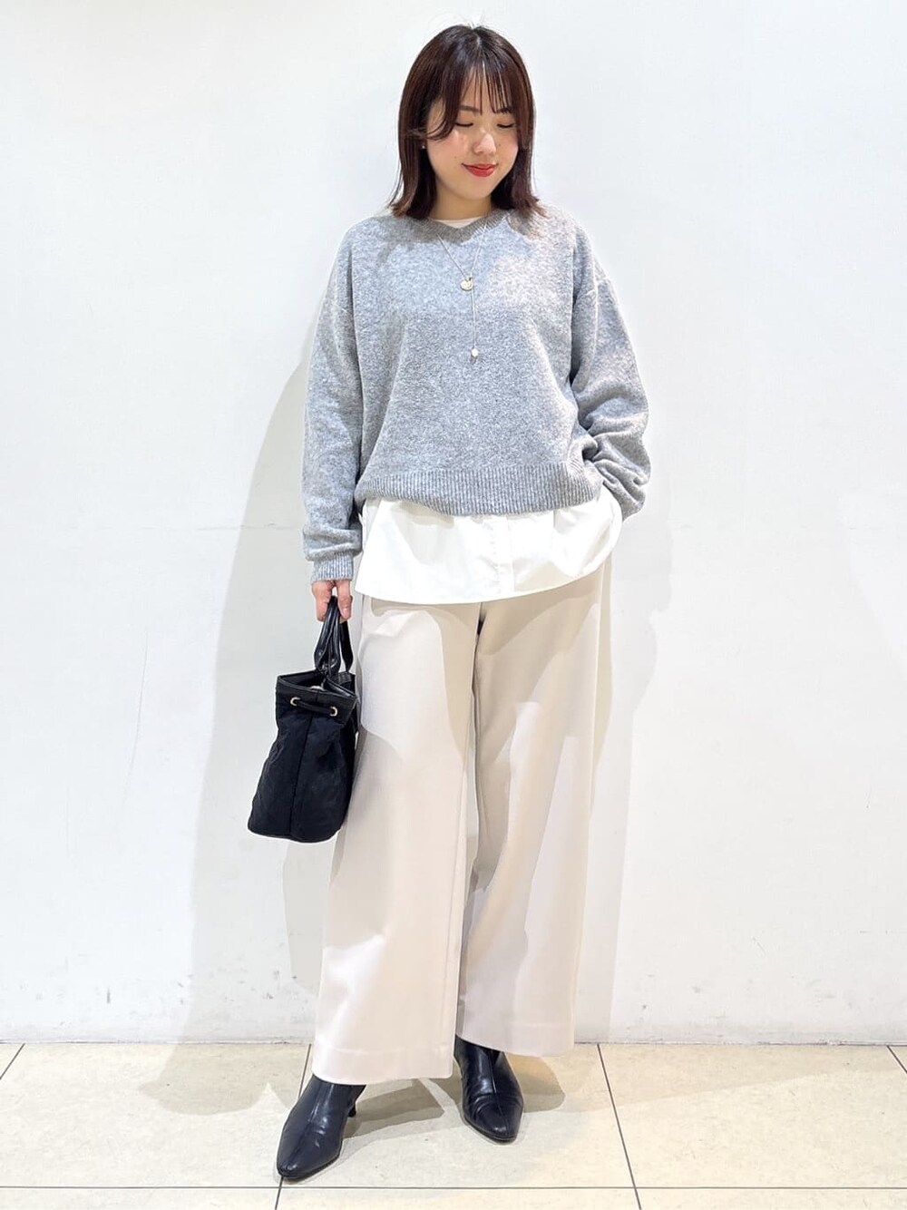 グレー系のニット/セーター、ホワイト系のTシャツ/カットソー、ベージュ系のその他パンツを着用したレディースの冬コーディネートの1枚目の写真
