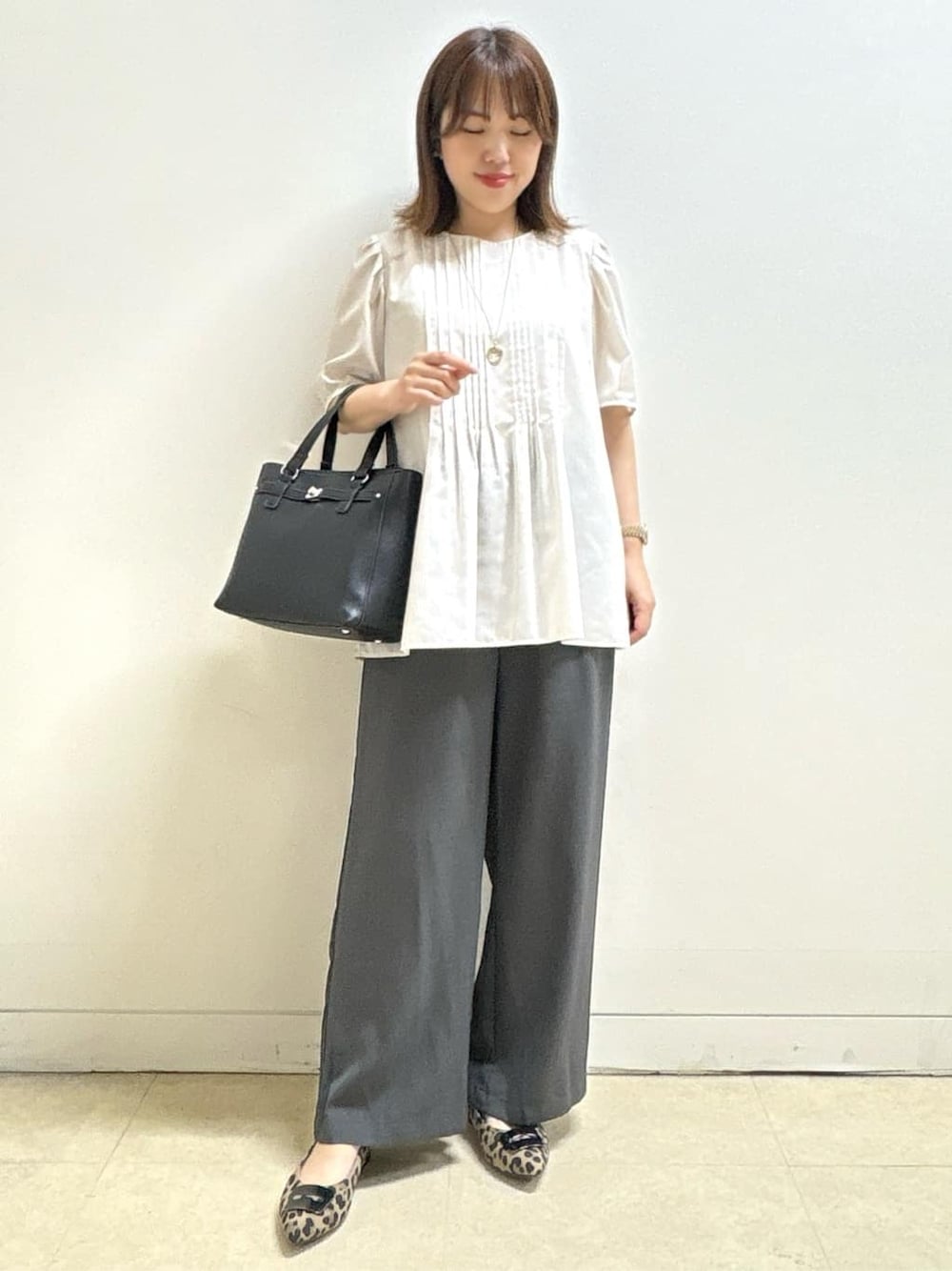 ベージュ系のシャツ/ブラウス、ベージュ系のパンプス、ブラック系のハンドバッグを着用したレディースの秋コーディネートの1枚目の写真