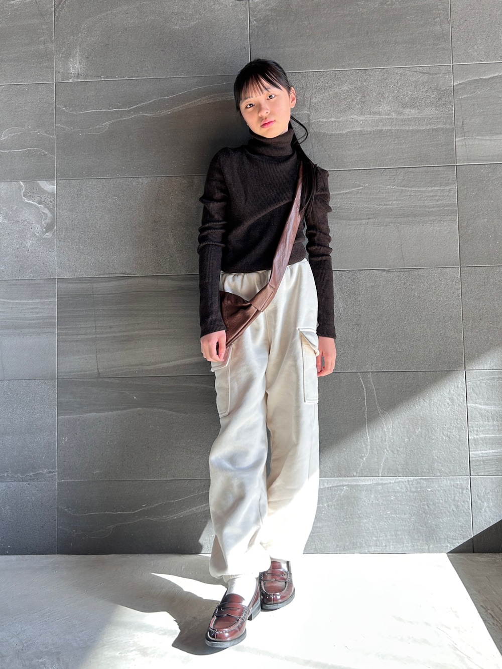 ブラウン系のニット/セーター、ホワイト系のスウェットパンツ、ブラウン系のショルダーバッグを着用したキッズの冬コーディネートの1枚目の写真