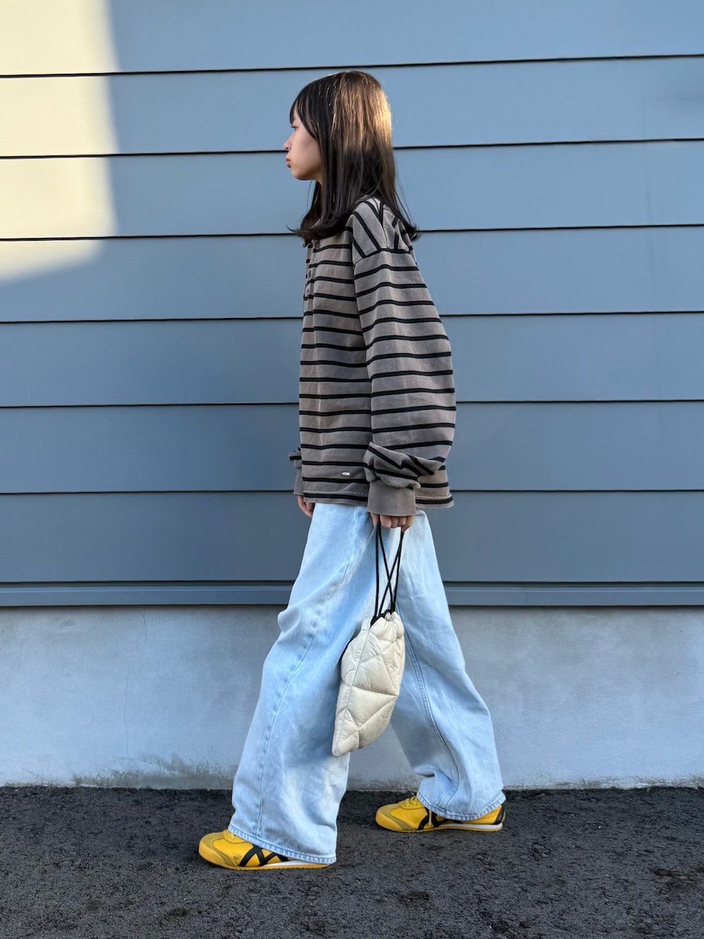 ベージュ系のショルダーバッグ、ブラウン系のTシャツ/カットソー、イエロー系のスニーカーを着用したキッズの秋コーディネートの1枚目の写真