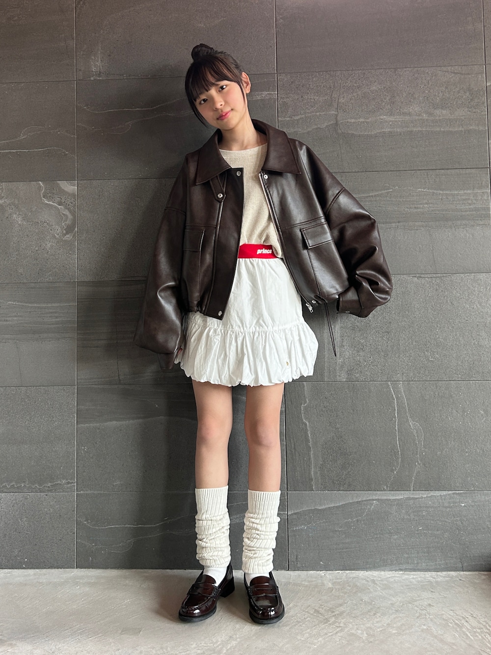 ブラウン系のブルゾン、ホワイト系のスカート、ベージュ系のTシャツ/カットソーを着用したキッズの冬コーディネートの1枚目の写真