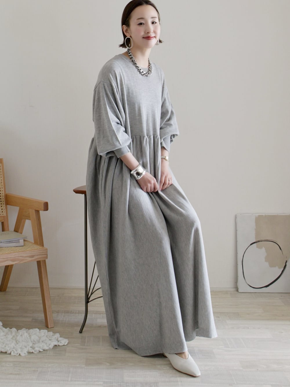 グレー系のワンピース、ホワイト系のパンプス、シルバー系のバングル/リストバンドを着用したレディースの冬コーディネートの1枚目の写真