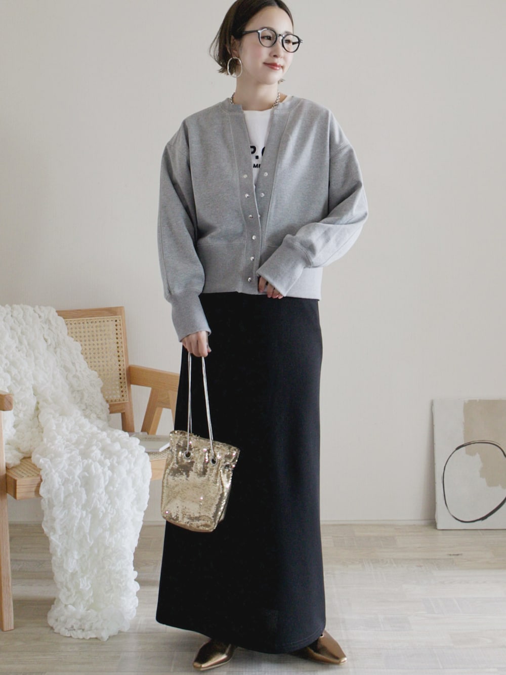 グレー系のカーディガン/ボレロ、ブラック系のスカート、ゴールド系のパンプスを着用したレディースの春コーディネートの1枚目の写真