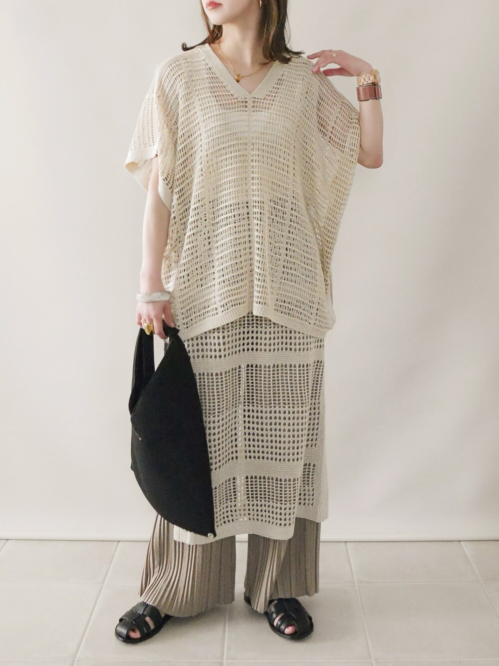 ベージュ系のニット/セーター、ベージュ系のワンピース、ブラック系のサンダルを着用したレディースの春コーディネートの1枚目の写真