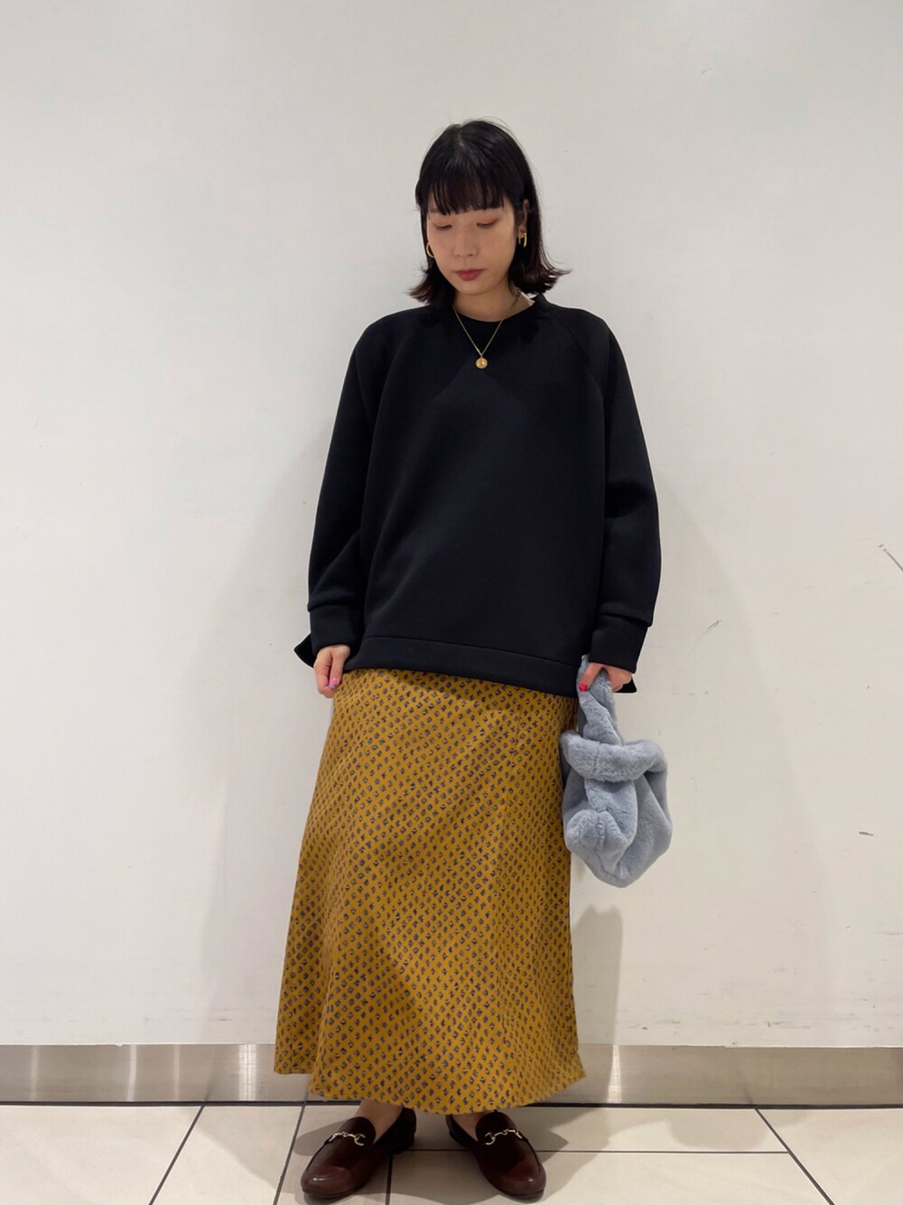 ブルー系のトートバッグ、ブラウン系のローファー、ブラック系のその他を着用したレディースの秋コーディネートの1枚目の写真