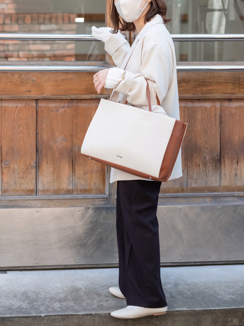 イエロー系のトートバッグ、ホワイト系のバレエシューズ、ホワイト系のテーラードジャケットを着用したレディースの春コーディネートの1枚目の写真