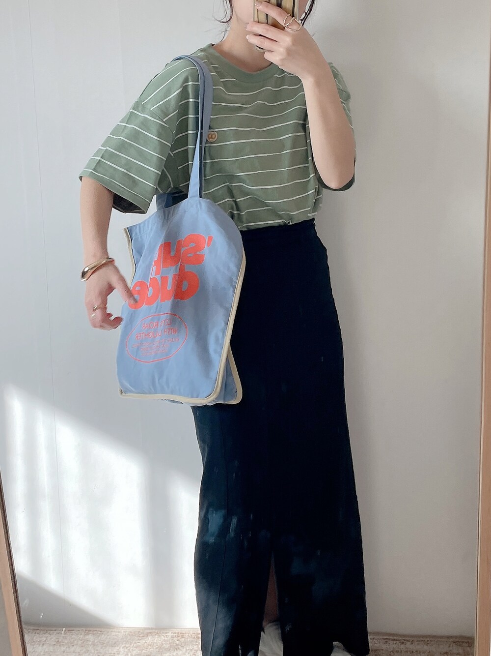 ブルー系のトートバッグ、グリーン系のTシャツ/カットソー、ホワイト系のスニーカーを着用したレディースの春コーディネートの1枚目の写真