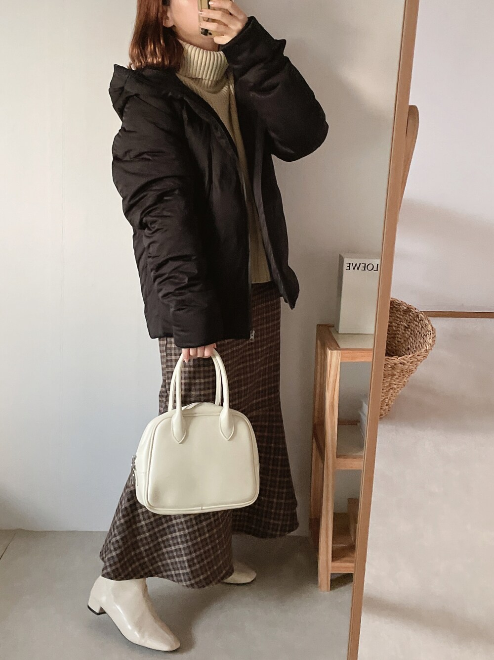 ブラック系のダウンジャケット/コート、ホワイト系のボストンバッグ、ホワイト系のニット/セーターを着用したレディースの秋コーディネートの1枚目の写真