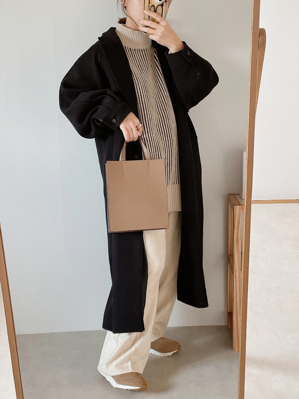 ベージュ系のバッグ、ブラック系のチェスターコート、ブラウン系のベストを着用したレディースの秋コーディネートの1枚目の写真