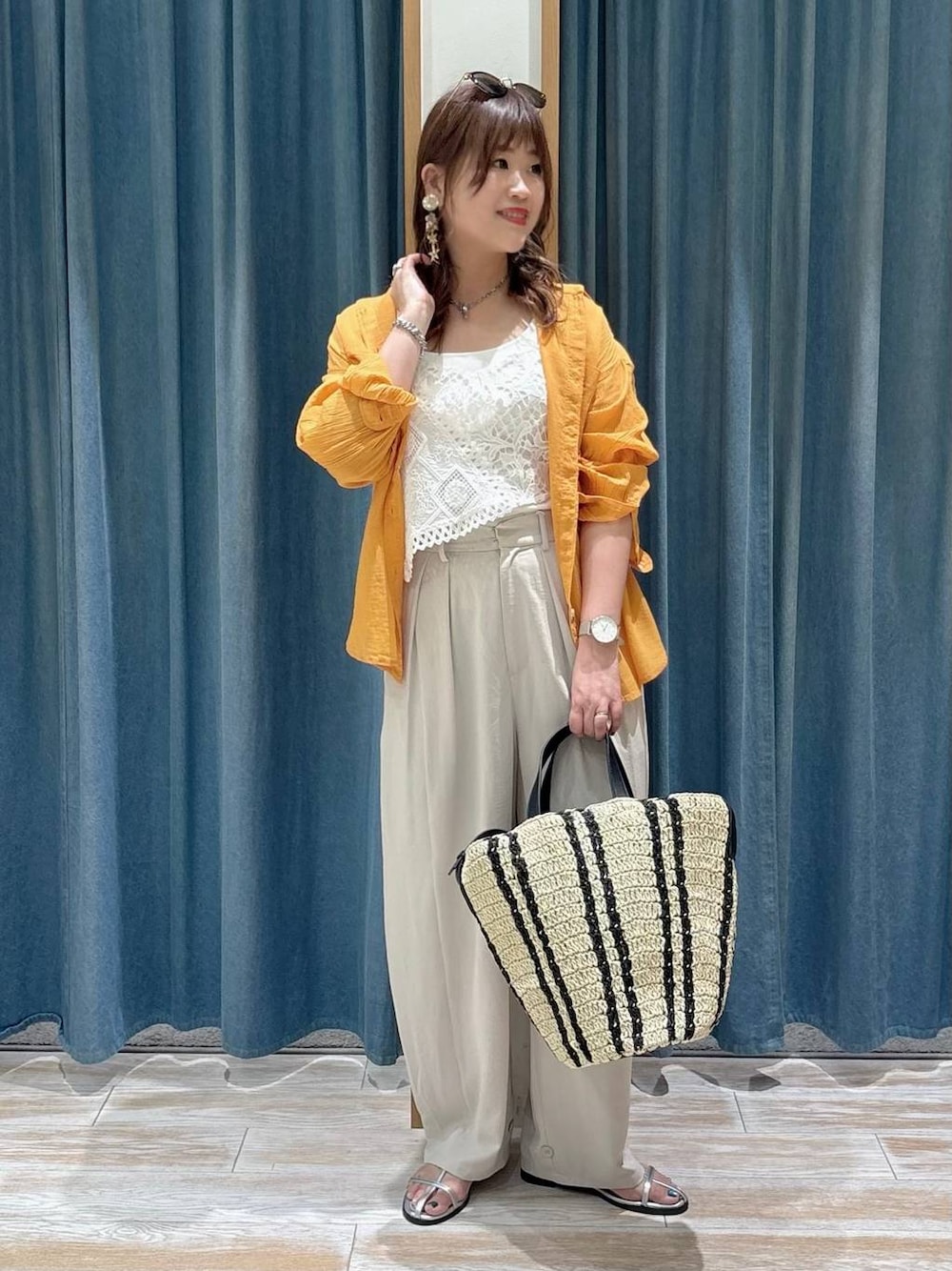 オレンジ系のシャツ/ブラウス、ベージュ系のトートバッグ、シルバー系のサンダルを着用したレディースの春コーディネートの1枚目の写真