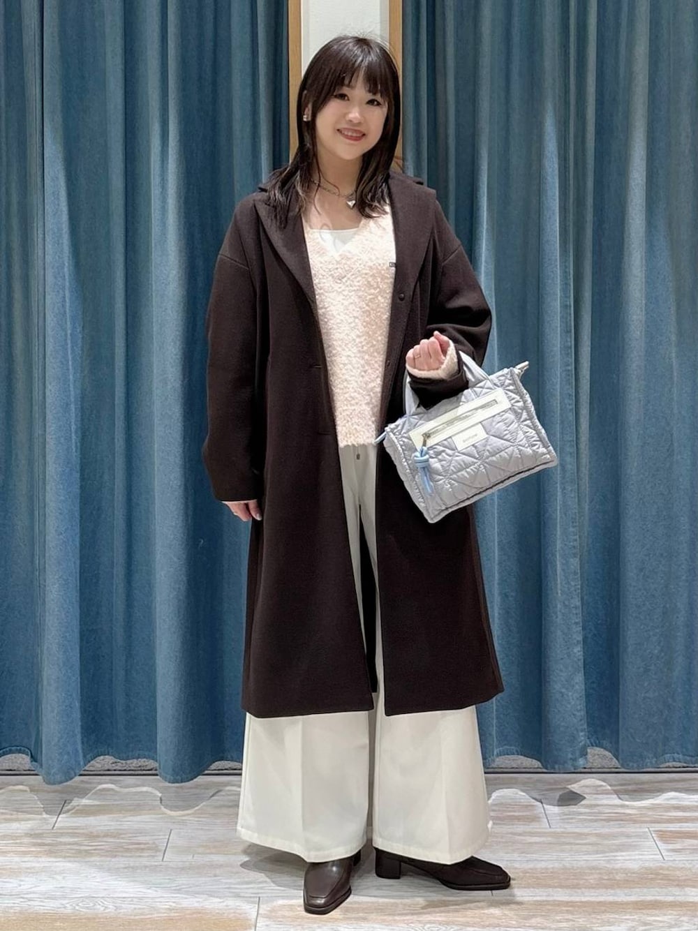 グレー系のショルダーバッグ、ベージュ系のその他パンツ、ブラウン系のチェスターコートを着用したレディースの冬コーディネートの1枚目の写真