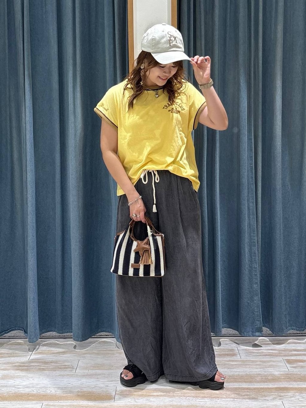 ブラック系のデニムパンツ、ブルー系のショルダーバッグ、イエロー系のTシャツ/カットソーを着用したレディースの夏コーディネートの1枚目の写真