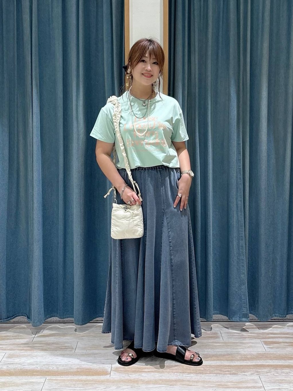 グリーン系のTシャツ/カットソー、ブラック系のサンダル、ブルー系のスカートを着用したレディースの夏コーディネートの1枚目の写真