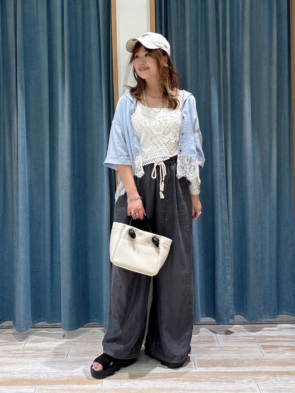 ブラック系のデニムパンツ、ベージュ系のショルダーバッグ、ホワイト系のキャミソールを着用したレディースの夏コーディネートの1枚目の写真