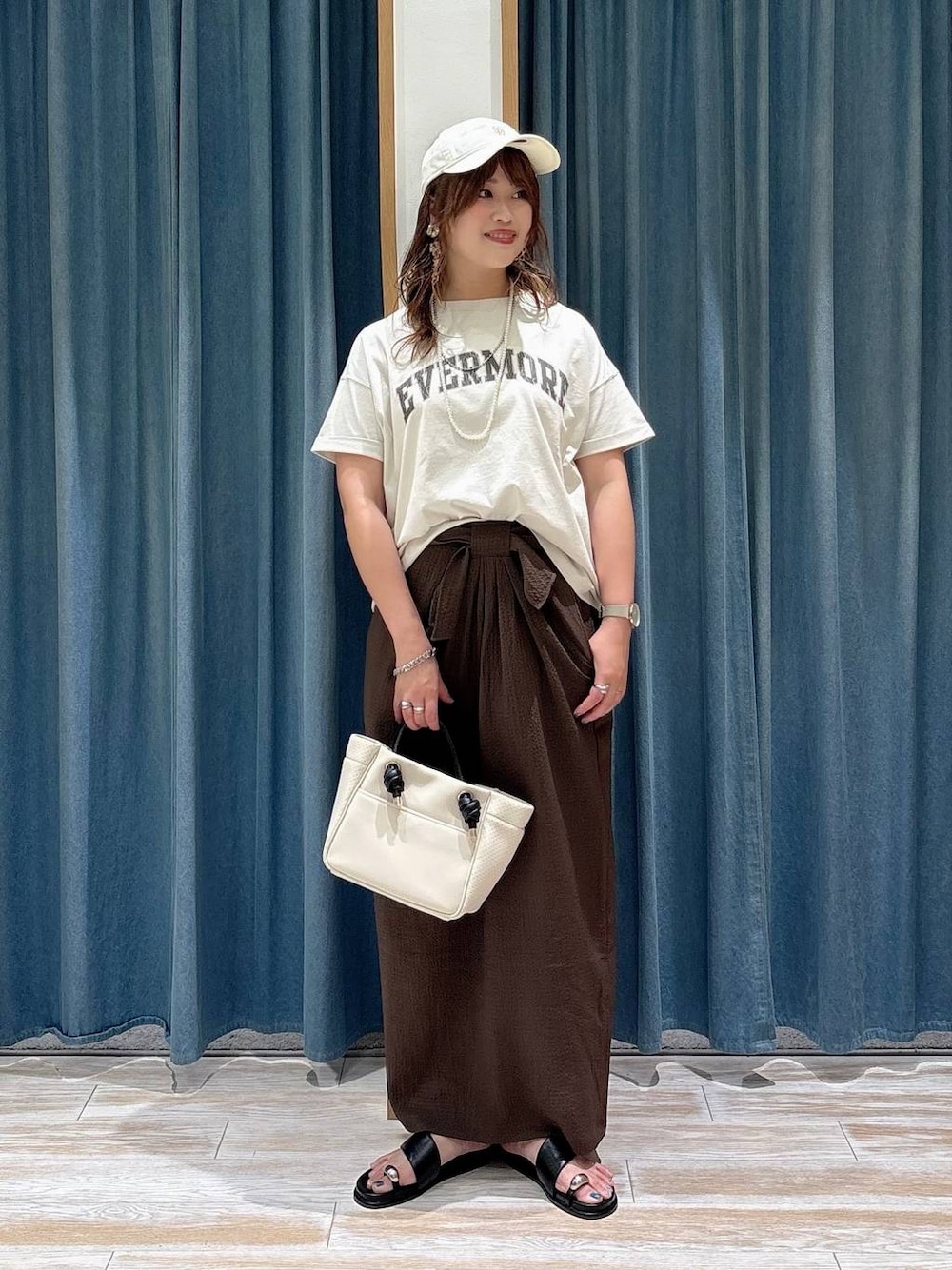 ホワイト系のTシャツ/カットソー、ブラック系のサンダル、ベージュ系のショルダーバッグを着用したレディースの夏コーディネートの1枚目の写真