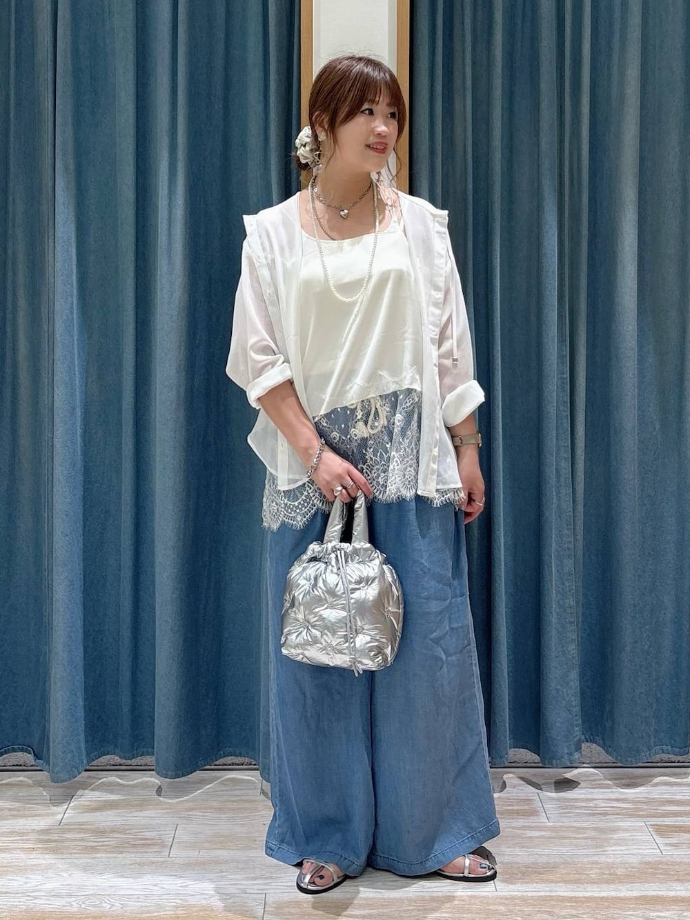 ブルー系のデニムパンツ、シルバー系のショルダーバッグ、シルバー系のサンダルを着用したレディースの春コーディネートの1枚目の写真