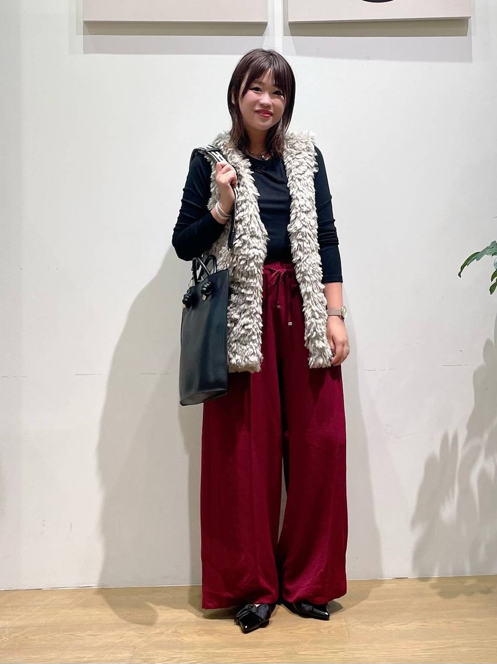 ブラック系のパンプス、ベージュ系のベスト、レッド系のその他パンツを着用したレディースの秋コーディネートの1枚目の写真