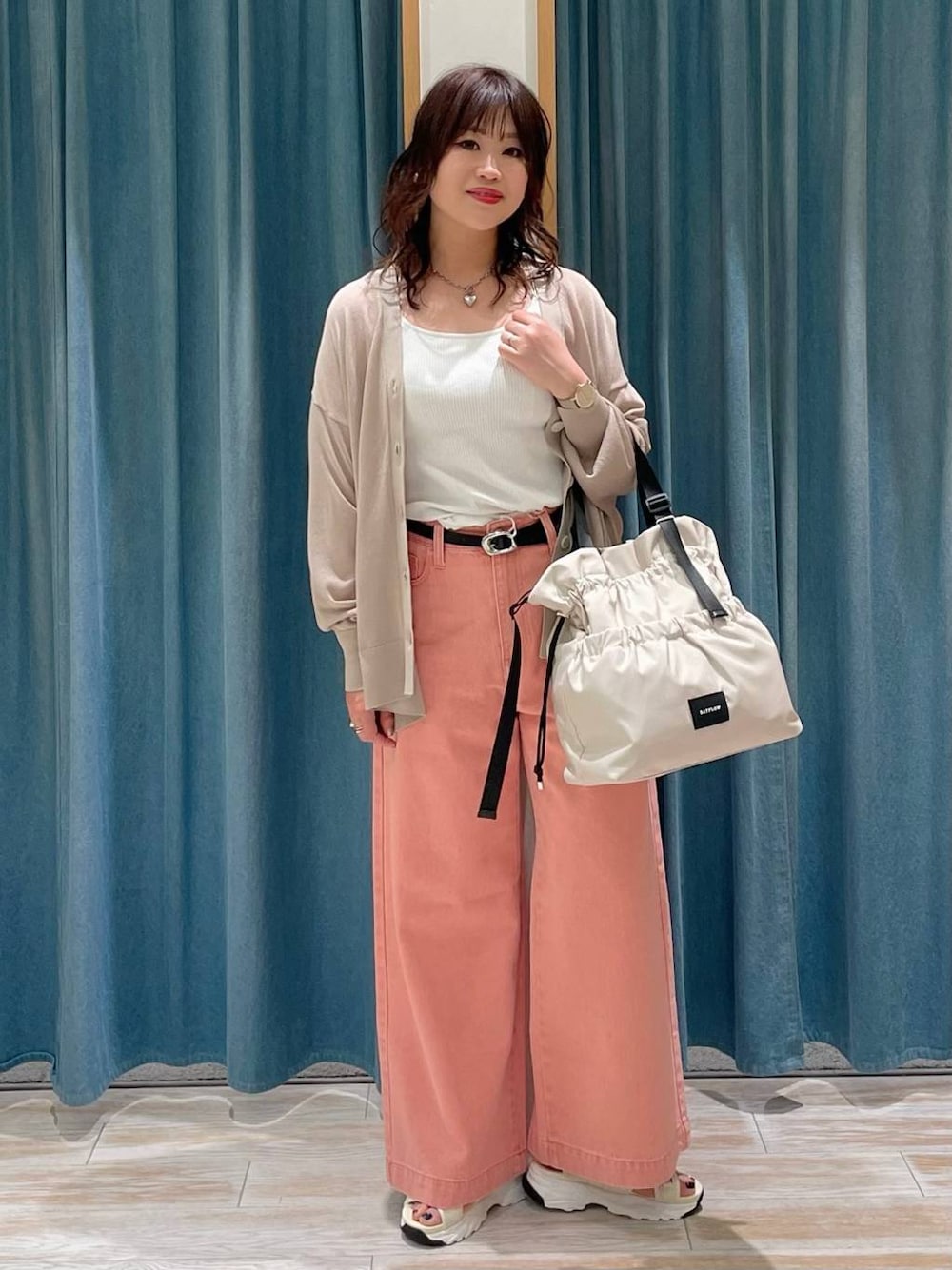 ホワイト系のキャミソール、ホワイト系のトートバッグ、ピンク系のデニムパンツを着用したレディースの春コーディネートの1枚目の写真