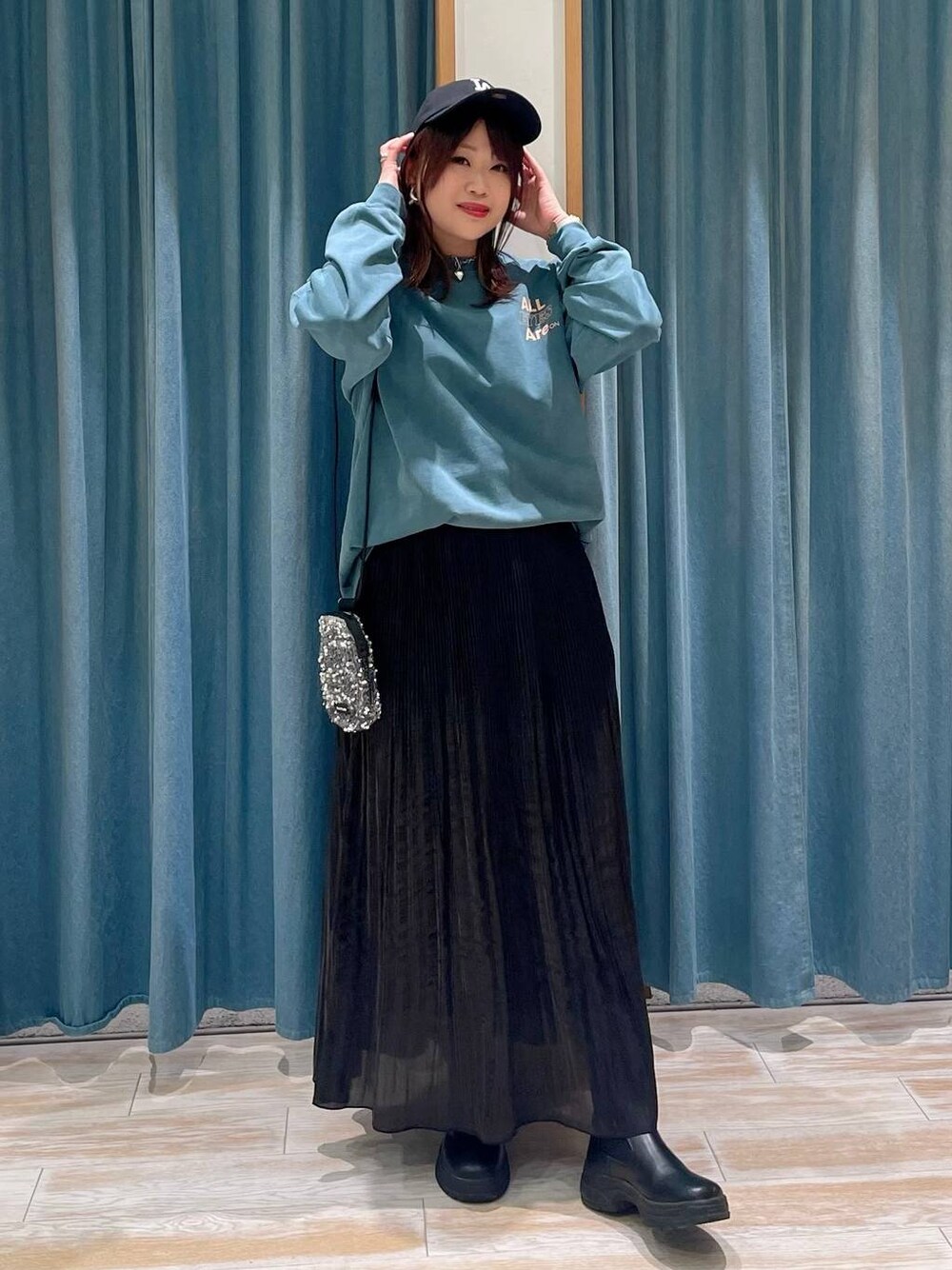 グレー系のショルダーバッグ、ブラック系のブーツ、ブラック系のスカートを着用したレディースの冬コーディネートの1枚目の写真