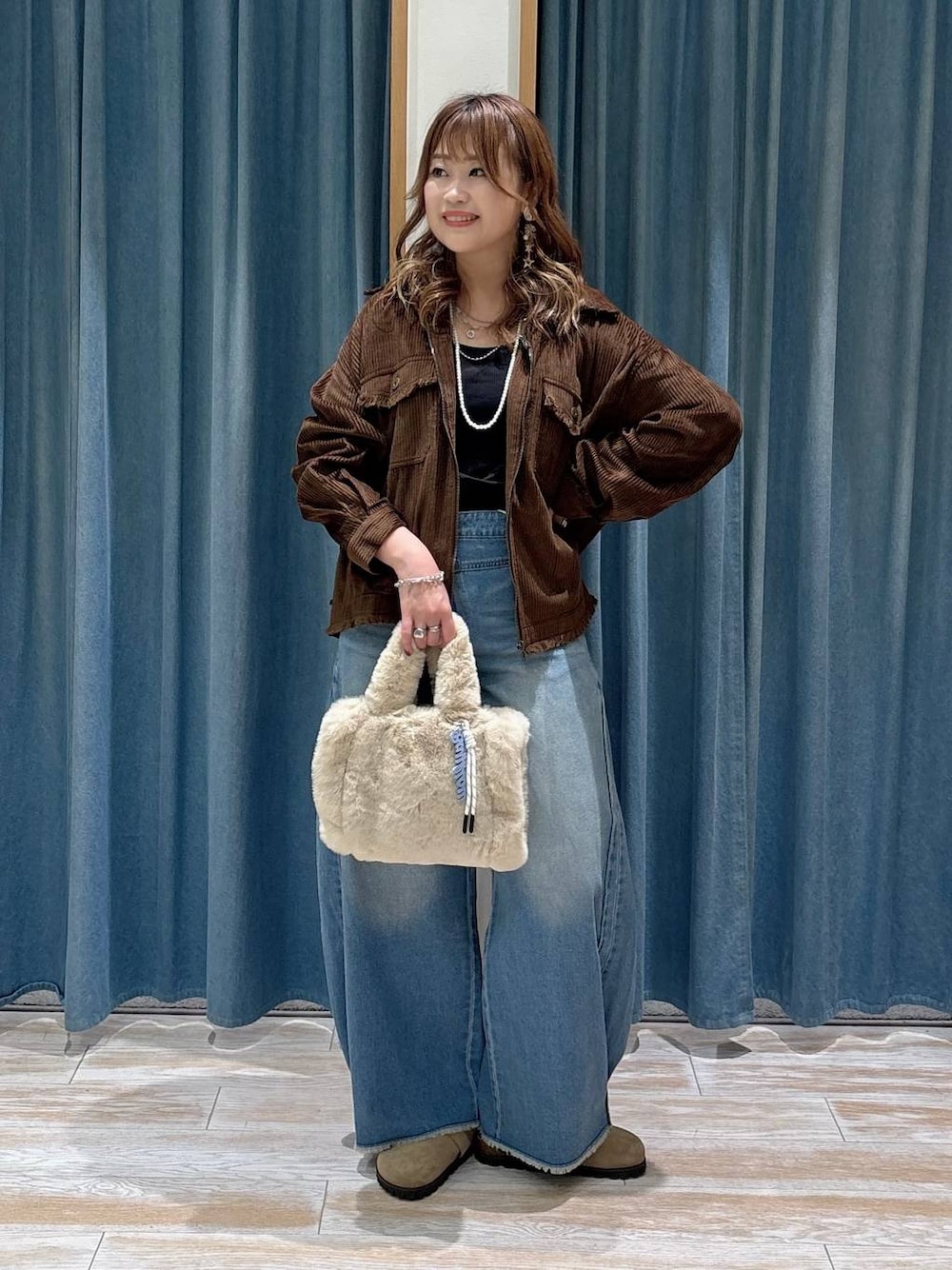 ブラウン系のブルゾン、ベージュ系のその他シューズ、ブルー系のデニムパンツを着用したレディースの秋コーディネートの1枚目の写真