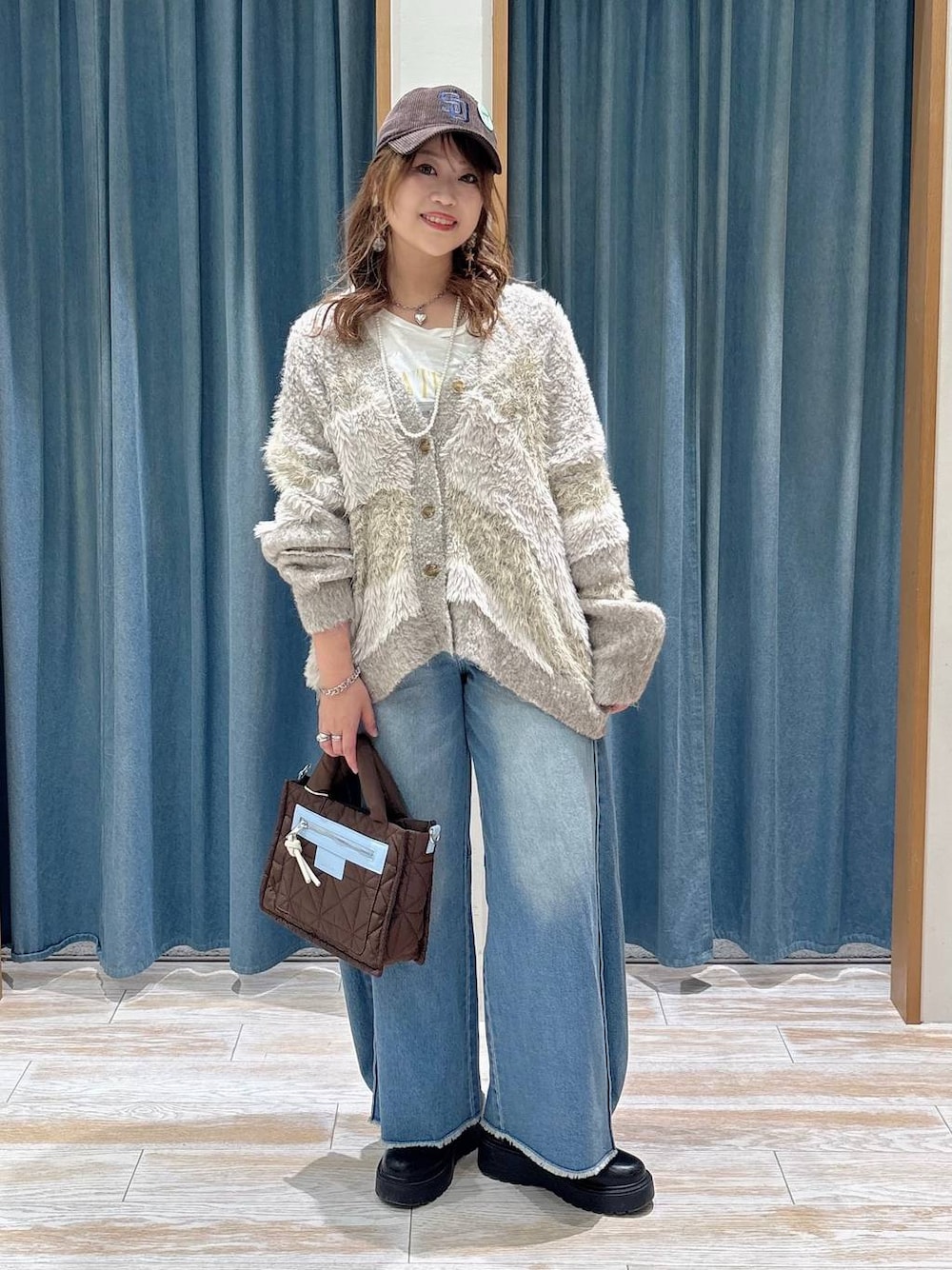 ベージュ系のカーディガン/ボレロ、ブルー系のデニムパンツ、ブラウン系のショルダーバッグを着用したレディースの秋コーディネートの1枚目の写真