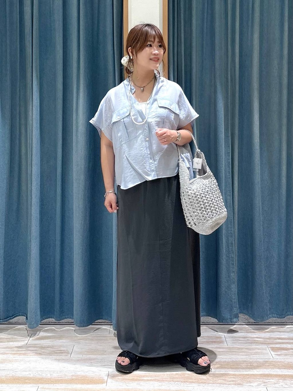 ブルー系のシャツ/ブラウス、グレー系のスカート、シルバー系のショルダーバッグを着用したレディースの夏コーディネートの1枚目の写真