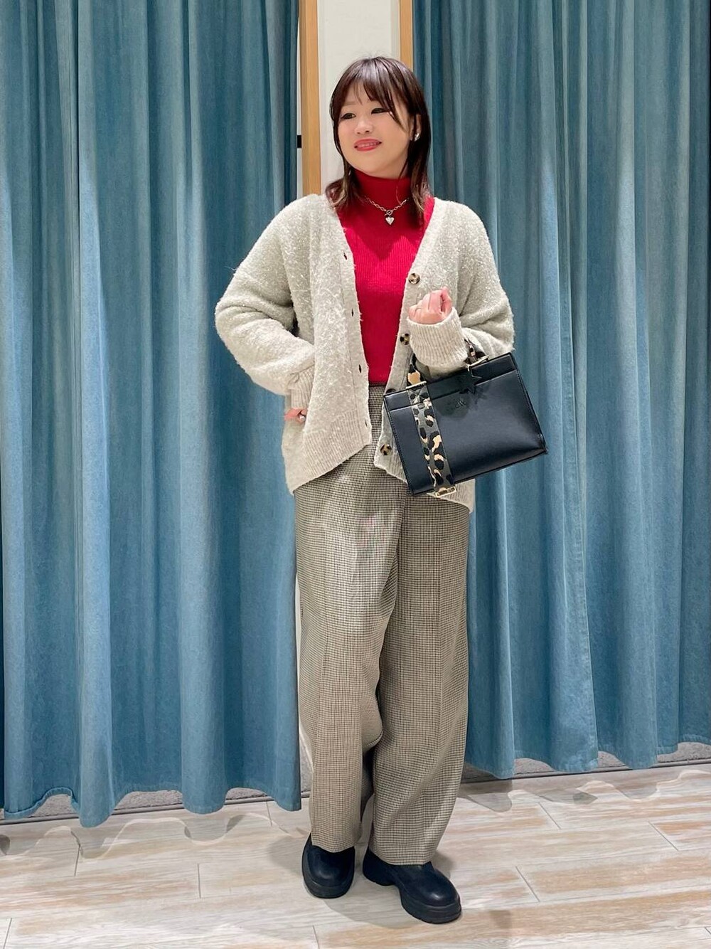 レッド系のニット/セーター、ブラック系のブーツ、ホワイト系のカーディガン/ボレロを着用したレディースの冬コーディネートの1枚目の写真