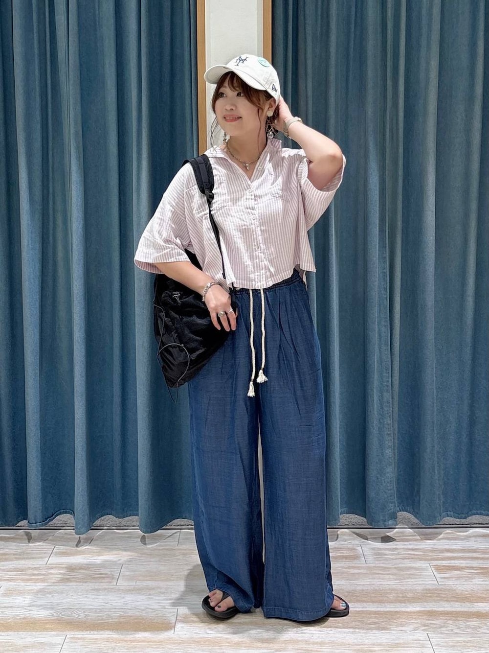 ブラック系のバックパック/リュック、ブルー系のデニムパンツ、ブラック系のサンダルを着用したレディースの夏コーディネートの1枚目の写真