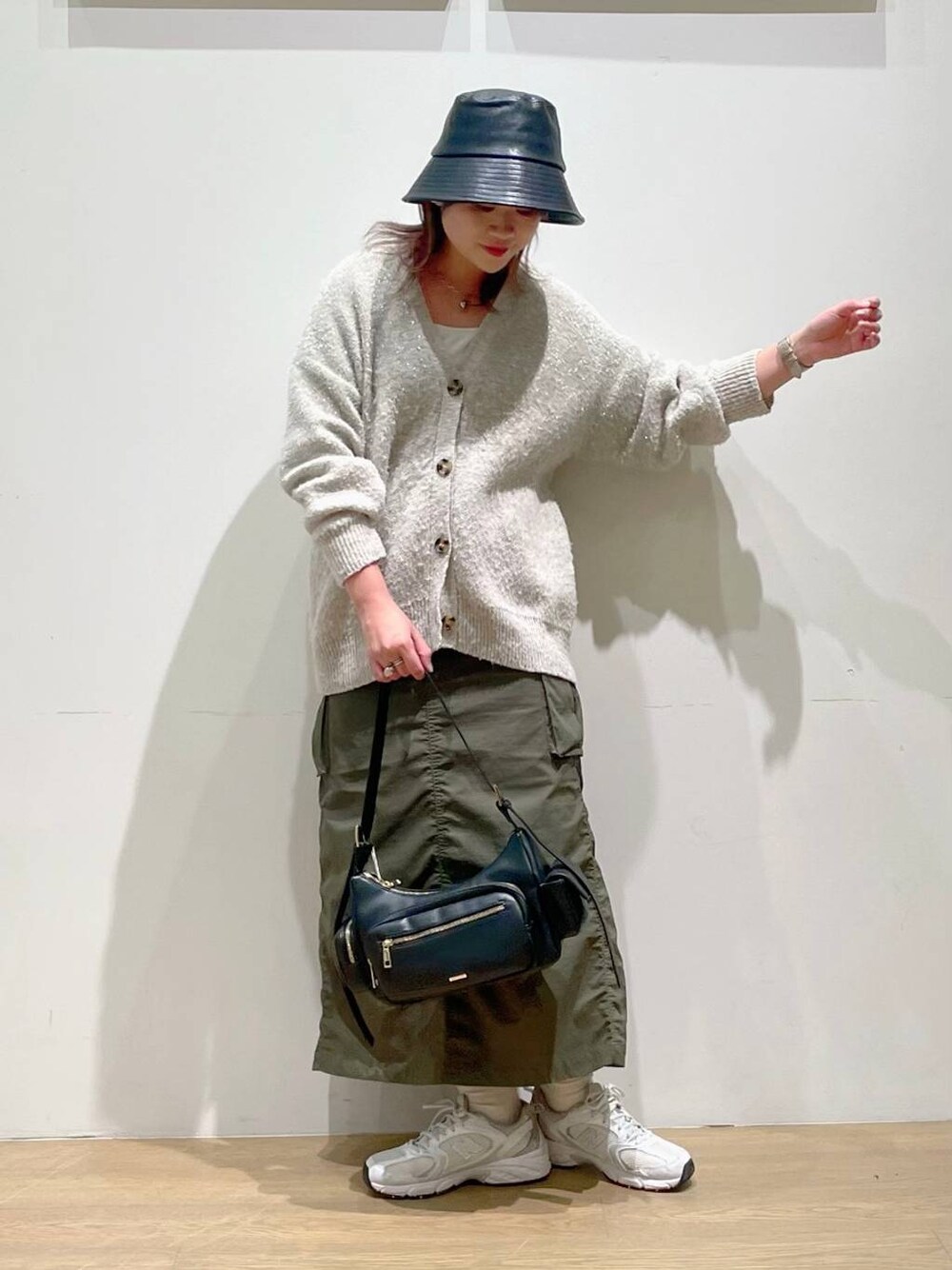 グリーン系のスカート、ホワイト系のキャミソール、ブラック系のハンドバッグを着用したレディースの秋コーディネートの1枚目の写真