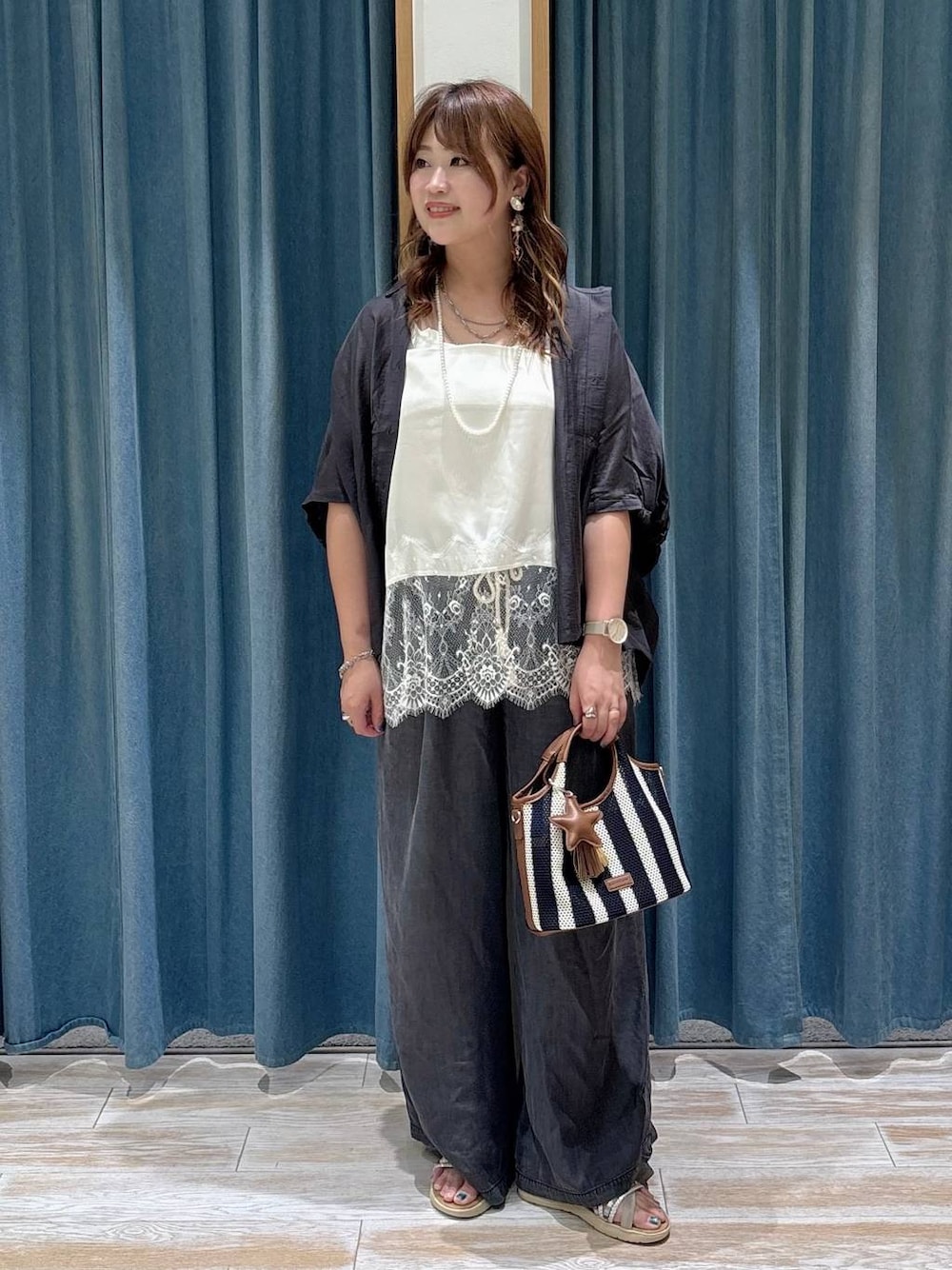 ブラック系のデニムパンツ、ブルー系のショルダーバッグ、シルバー系のサンダルを着用したレディースの夏コーディネートの1枚目の写真