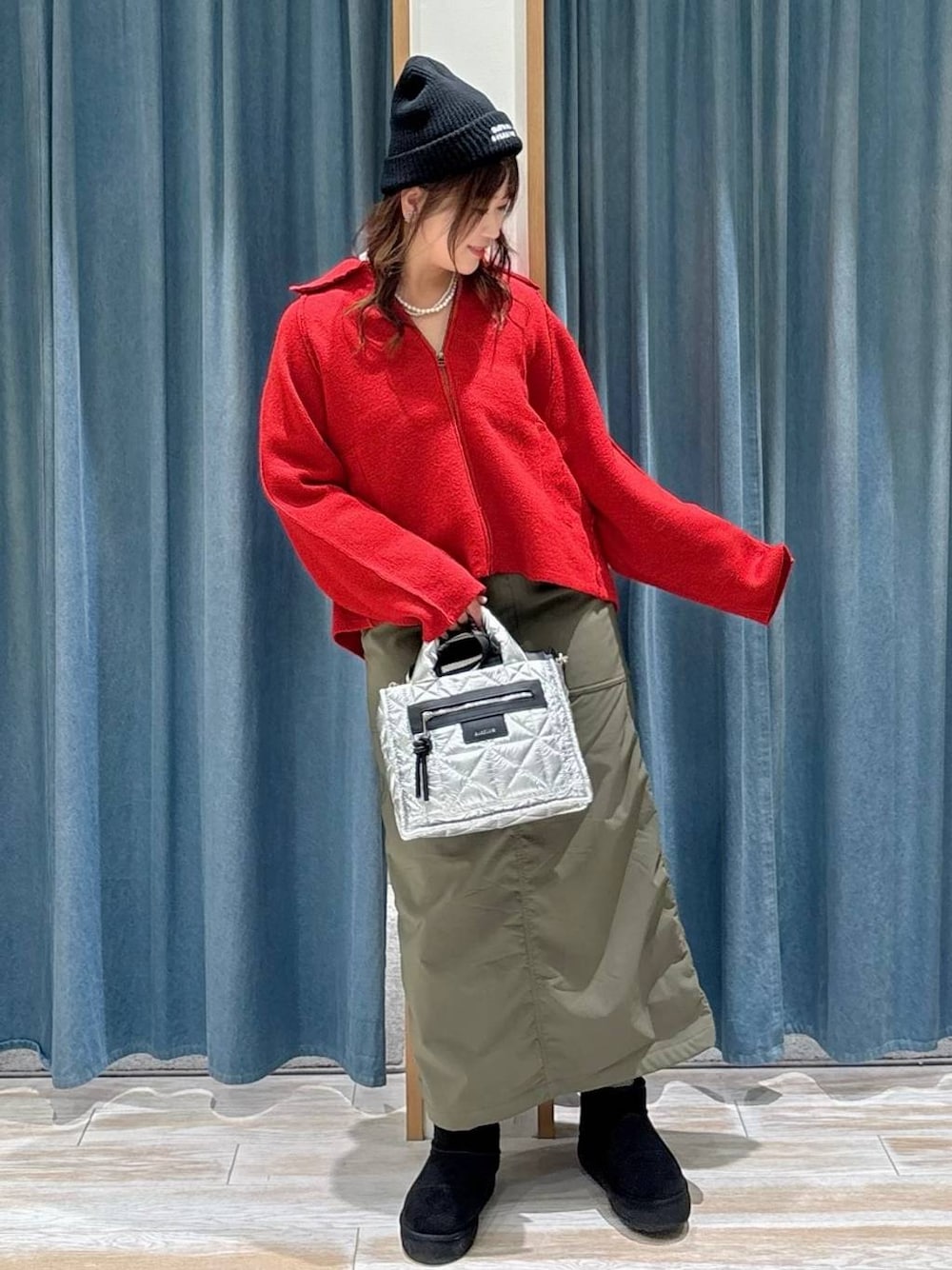 シルバー系のショルダーバッグ、グリーン系のスカート、ブラック系のブーツを着用したレディースの秋コーディネートの1枚目の写真