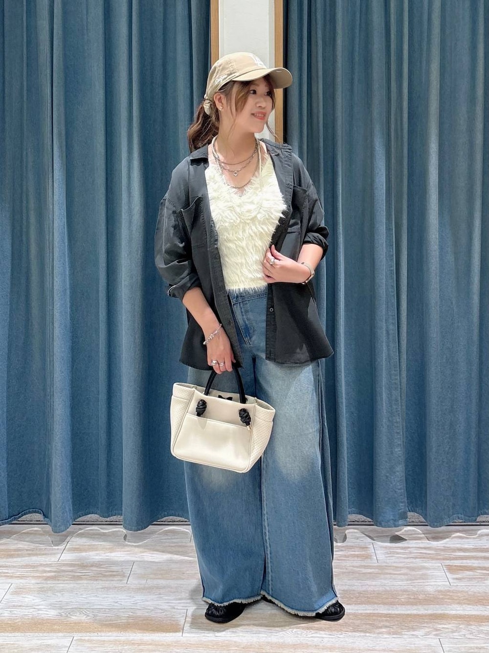 ブラック系のスリッポン、ホワイト系のベスト、ブルー系のデニムパンツを着用したレディースの夏コーディネートの1枚目の写真
