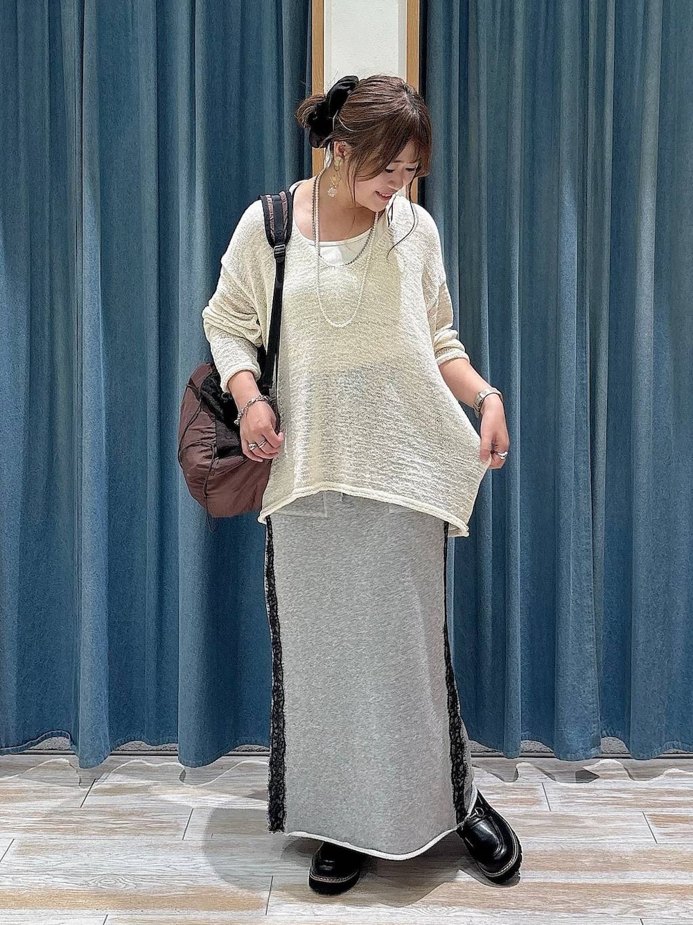 ブラウン系のバックパック/リュック、ホワイト系のニット/セーター、グレー系のスカートを着用したレディースの夏コーディネートの1枚目の写真