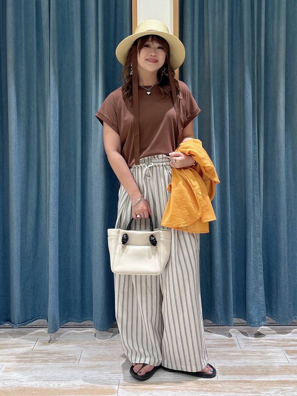 オレンジ系のシャツ/ブラウス、ホワイト系のその他パンツ、ベージュ系のショルダーバッグを着用したレディースの春コーディネートの1枚目の写真