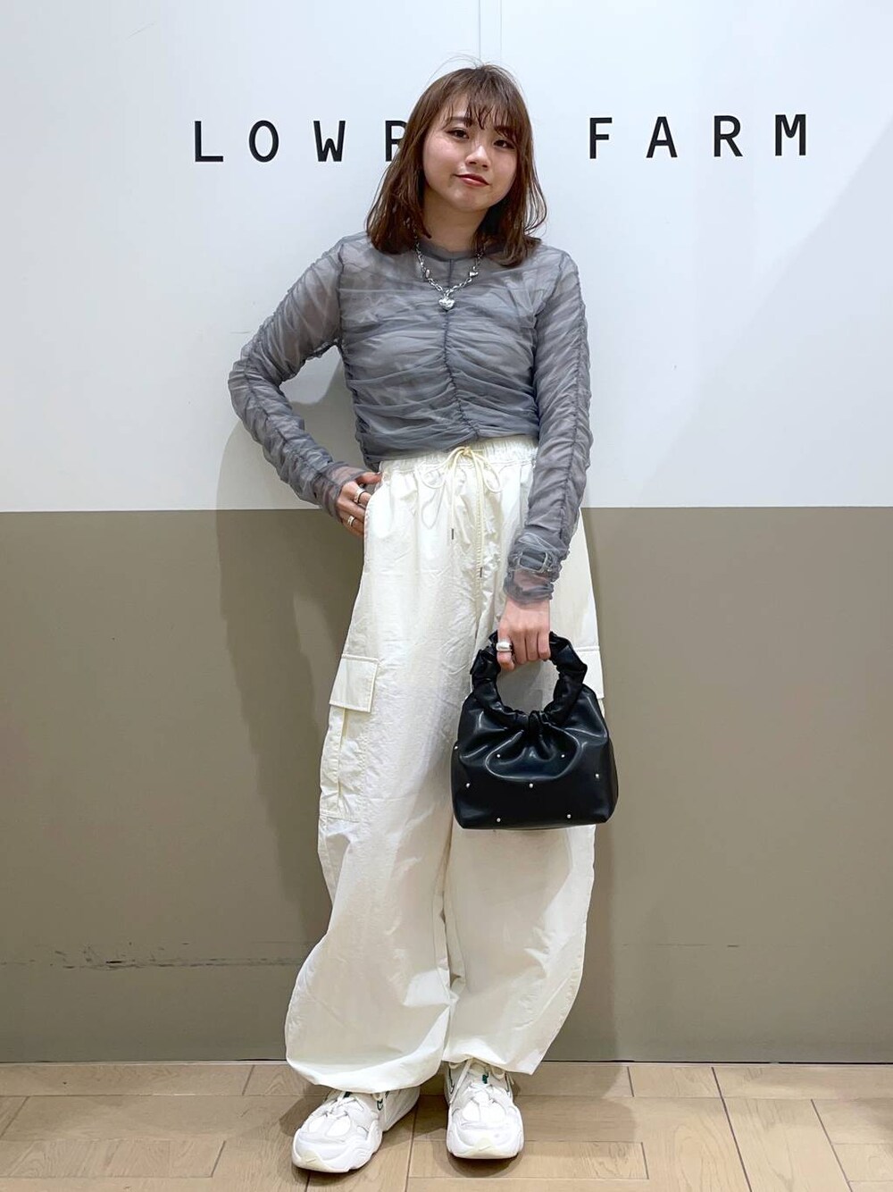 グレー系のシャツ/ブラウス、ブラック系のハンドバッグ、ホワイト系のカーゴパンツを着用したレディースの春コーディネートの1枚目の写真